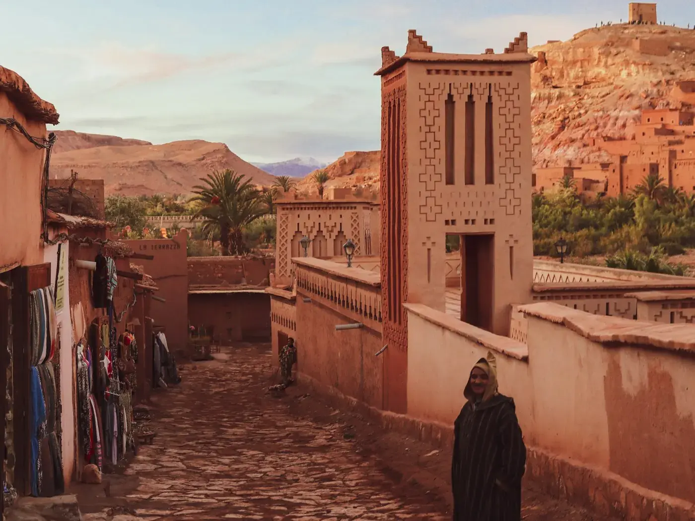 Visitors walking a path below the earthen walls of the ksar of Aït Benhaddou.