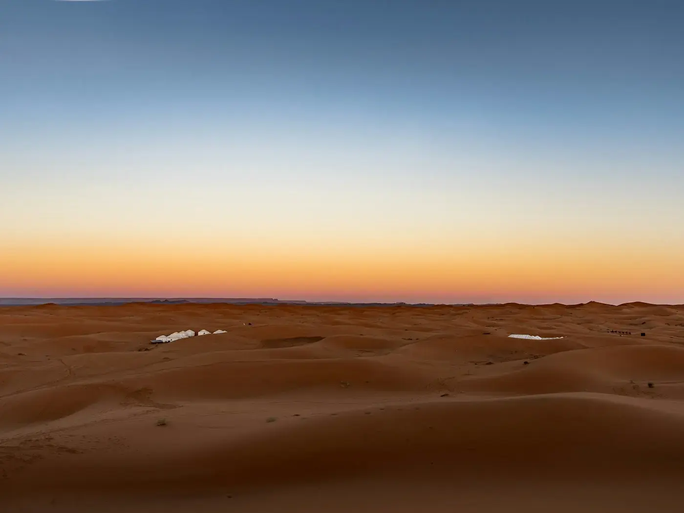 Sand dunes under a fading sky at sunset.